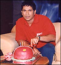 Tendulkar cuts a cricket ball-shaped cake during the interview