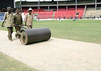 Ground staff roll a very cracked pitch as Australia train in the background at M.Chinnaswamy Stadium on October 4, 2004 in Bangalore, India.