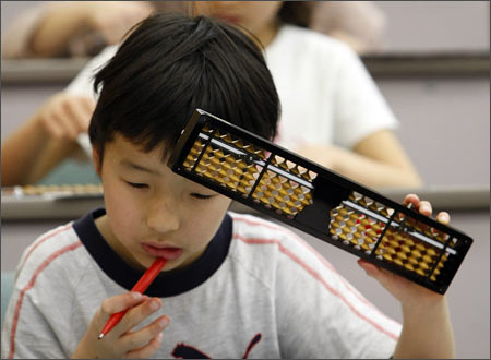 An elementary school boy holds a Japanese traditional calculating tool called the soroban (abacus)