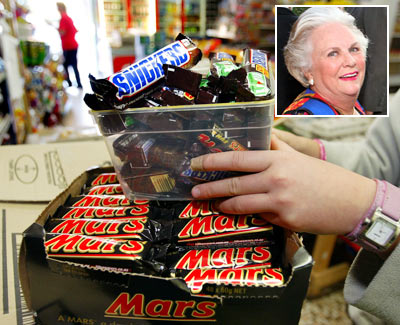 A shopkeeper removes Mars Bars and Snickers Bars from the shelves of her convenience store (Inset: Jacqueline Mars)