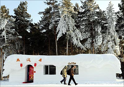 Tourists walk past a coffee shop covered by shaped snow ahead of the 13th Harbin Ice and Snow World in Harbin.