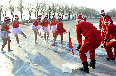 Winter swimmers wearing Santa Claus costumes play soccer on a frozen lake in Shenyang.