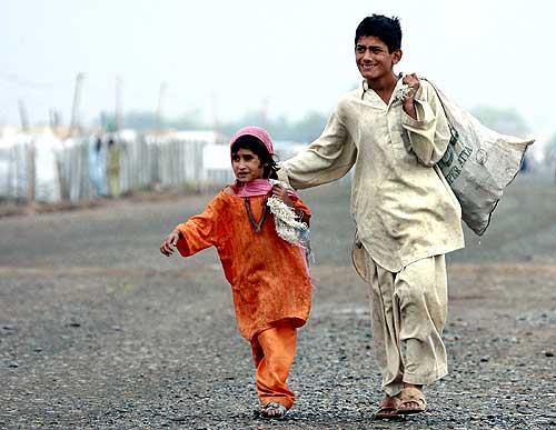 Evacuees from Buner walk near a camp on the outskirts of Peshawar