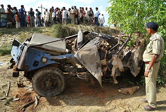 A policeman stands besides the wreckage of a security patrol vehicle that was damaged in a landmine blast in Bihar