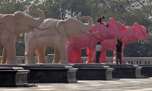 Workers cover elephant statues at a park in Noida