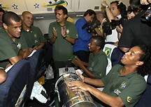 Brazil players Rivaldo, Roberto Carlos, Denilson and Roque Junior sing along as striker Ronaldinho bangs out a samba beat on a drum, during their flight home from Japan.