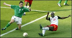 Cameroon's Patrick Mboma (R) scores as Ireland's Matt Holland tries to defend 