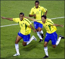 Rivaldo (L) throws his arms out wide as he celebrates his penalty goal with Denilson (C rear) and Edmilson (R).