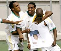 Siyabonga Nomvethe (R) displays a picture of his child on a t-shirt worn beneath his jersey while celebrating his goal with Quinton Fortune (L) and Teboho Mokoena.
