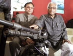 Defence Minister George Fernandes points to a tripod-mounted machine gun at the Defexpo India 2002
