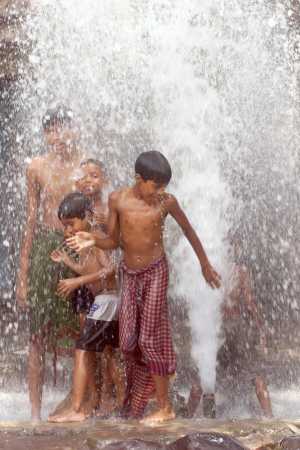 Street children bathe in water gushing out of a burst water pipe.