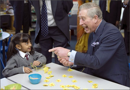 Britain's Prince Charles laughs as he sits with a girl during his visit to the Swaminarayan School to celebrate the Hindu festival of Holi, London March 4, 2009.