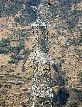 Electricity workers sit atop a newly constructed high-tension electricity tower.