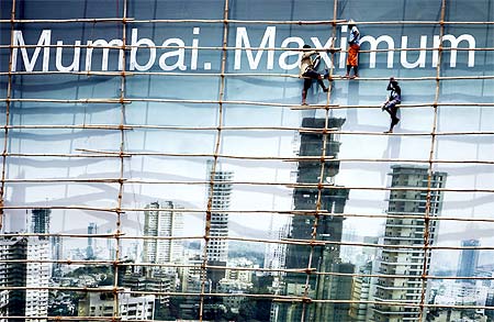 Labourers work on a billboard in Mumbai. Job-losses in India are likely to intensify, says a study.