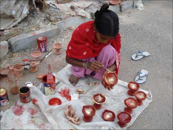 A girl makes earthen lamps.
