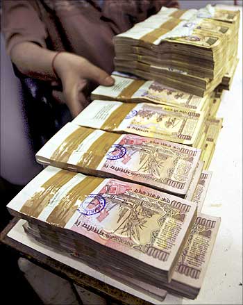 A bank employee counts bundles of Indian currency.