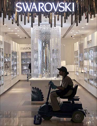 An employee operates a floor cleaning machine in front of a Swarovski showroom in Mumbai.