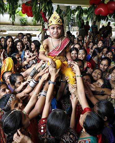 A boy dressed as Lord Krishna is carried during Janmashtami celebrations.