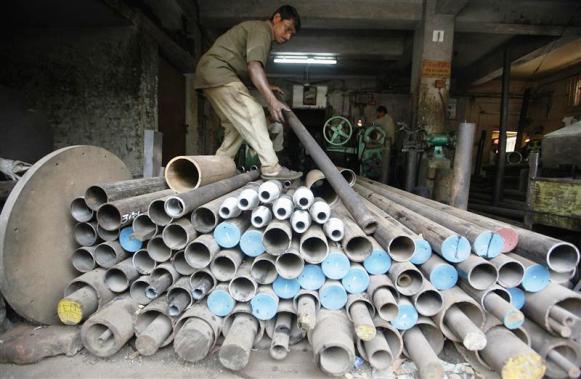 A worker checks an iron pipe that will be used to make spare parts for a drilling machine inside a factory in Kolkata.