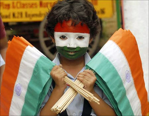 A school girl with her face painted in the colours of the Indian national flag holds flags during Independence Day celebrations at a school in Patna