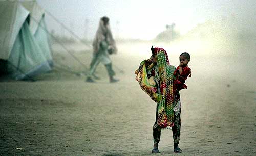 A girl and her sibling weathering a dust storm at the Yar Hussain camp