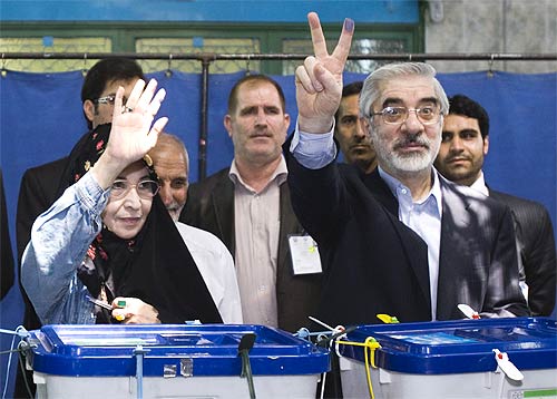 Hossein Mousavi flashes a victory sign after casting his vote with his wife Zahra Rahnavard in Teheran.