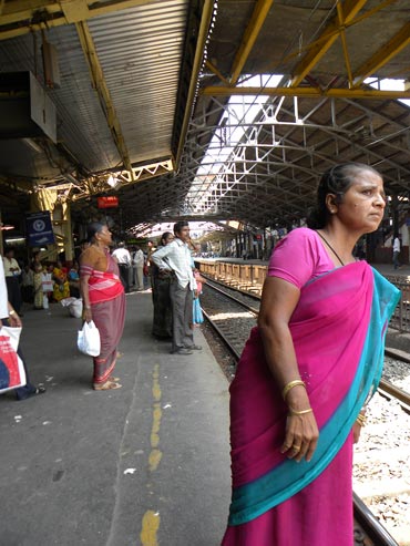 A woman cranes her neck, hoping to see a train in Mumbai