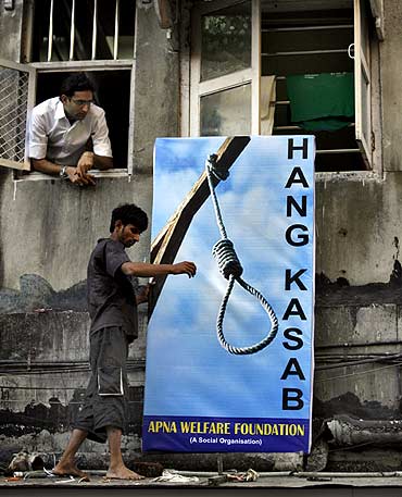 A resident places a billboard of Kasab outside a residential building near the Leopold Cafe, one of the sites of last year's terrorist attacks
