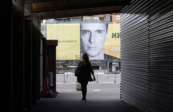 A pedestrian walks past a poster with the face of Russian billionaire Mikhail Prokhorov hanging near Moscow's Red Square