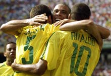 Edmilson (L) is hugged by team mates Ronaldo (C) and Rivaldo after scoring his team's third goal. 