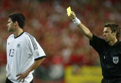 Swiss referee Urs Meier gives Michael Ballack a yellow card.